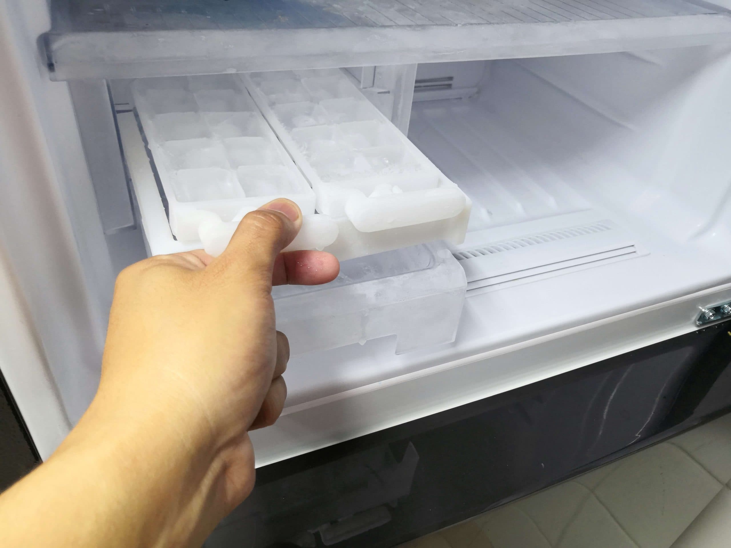 man checking ice in an ice maker refrigerator